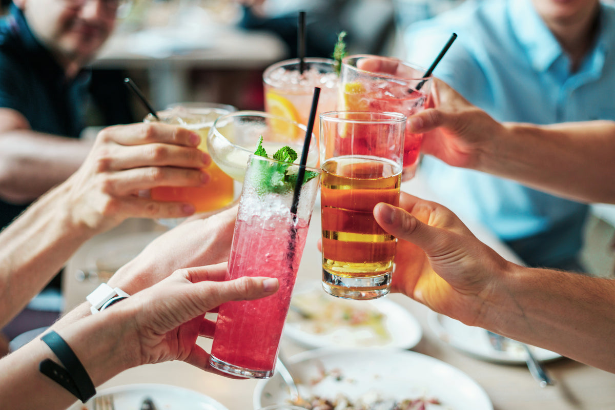 Fuenf Menschen mit Gläsern die im Restaurant anstoßen